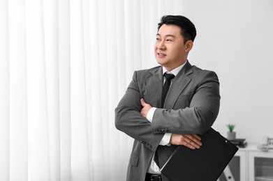 Photo of Portrait of happy notary with clipboard indoors, space for text