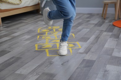 Photo of Little girl playing hopscotch at home, closeup