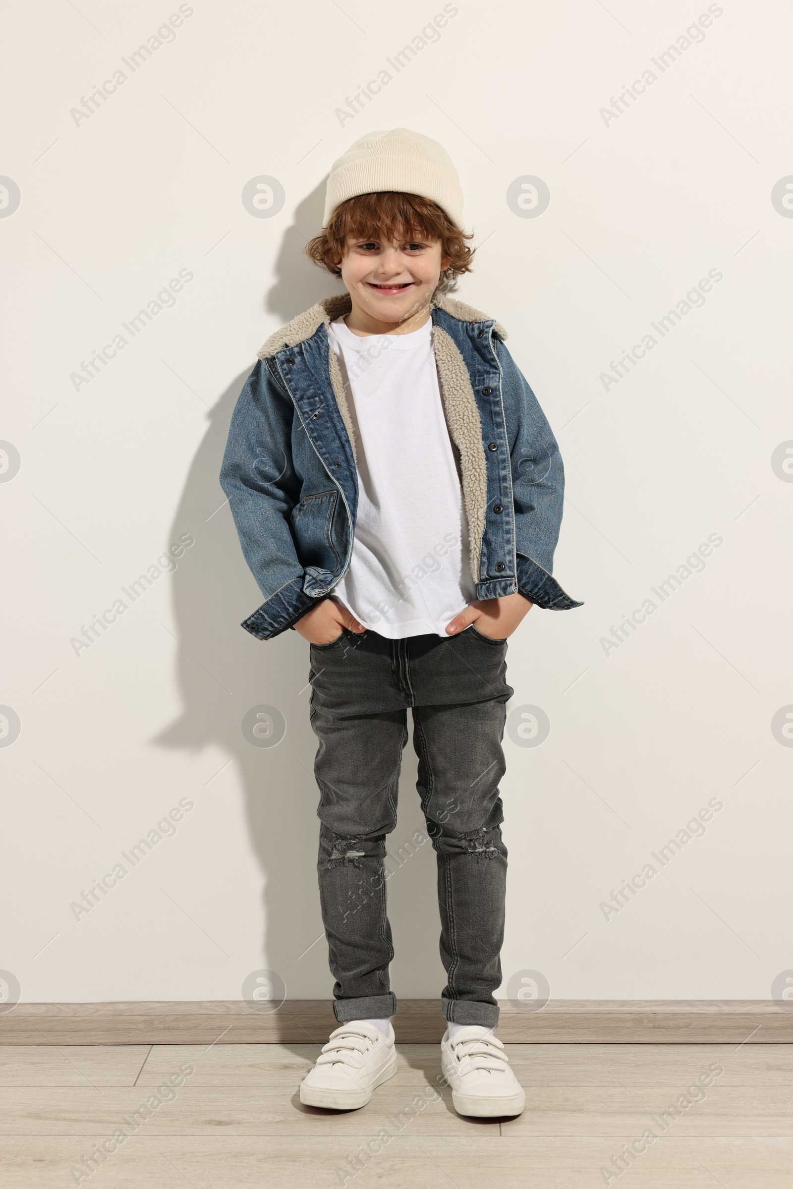 Photo of Fashion concept. Stylish boy posing near white wall