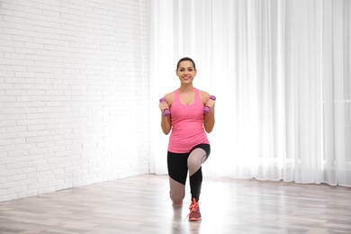 Photo of Young beautiful woman with dumbbells doing exercise at home. Workout and fitness
