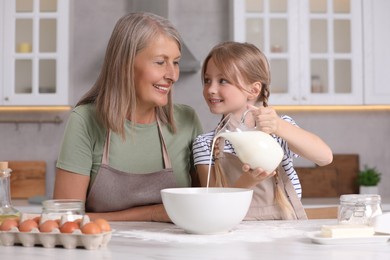 Photo of Happy grandmother with her granddaughter cooking together in kitchen