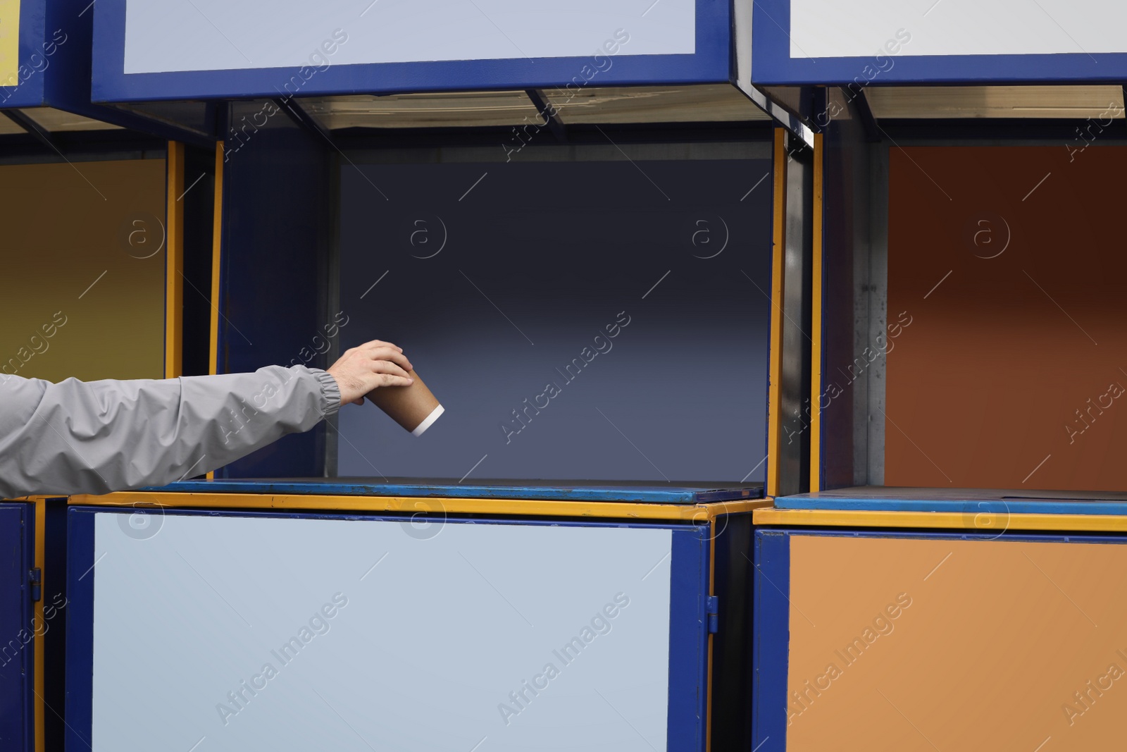 Photo of Man throwing paper coffee cup into garbage bin outdoors, closeup. Waste sorting