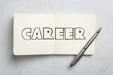 Photo of Notebook with word CAREER and pen on white table, top view