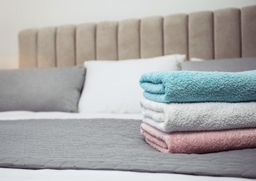 Photo of Stack of clean towels on bed, closeup. Space for text