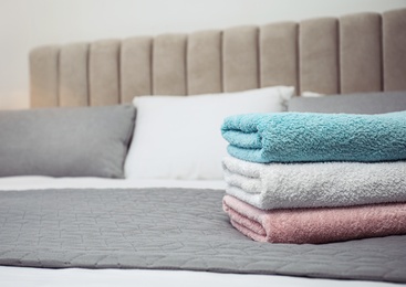 Stack of clean towels on bed, closeup. Space for text