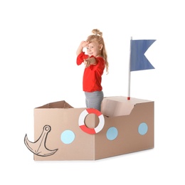 Cute little girl playing with cardboard ship on white background