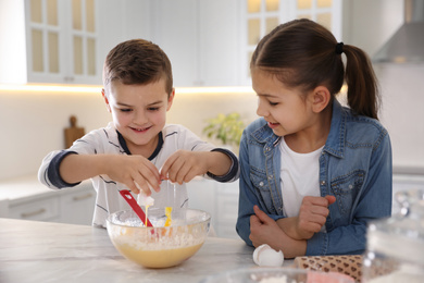 Photo of Cute little children cooking dough together in kitchen