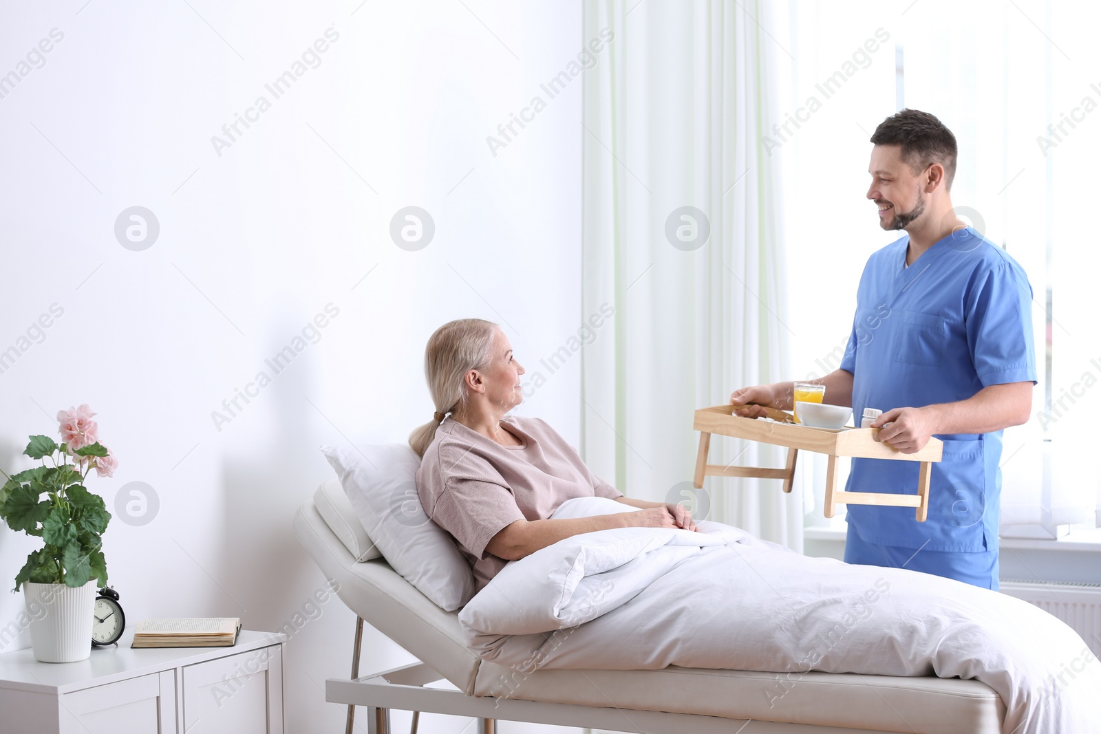 Photo of Male nurse bringing food and medicine for patient in hospital ward. Doctor's prescription