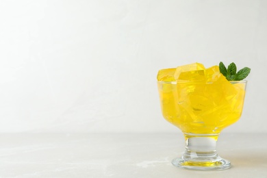 Photo of Dessert bowl with tasty jelly cubes on table. Space for text