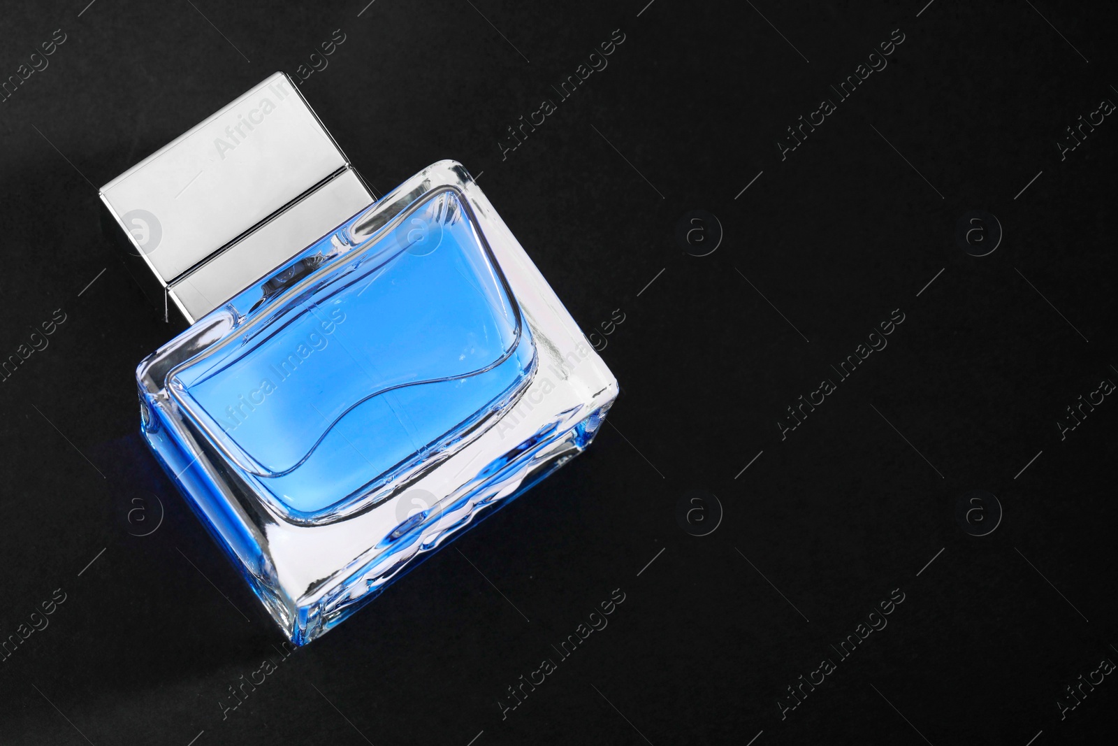 Photo of Blue men's perfume in bottle on black background, top view. Space for text