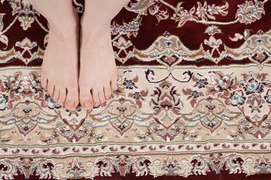 Photo of Woman standing on carpet with pattern at home, top view