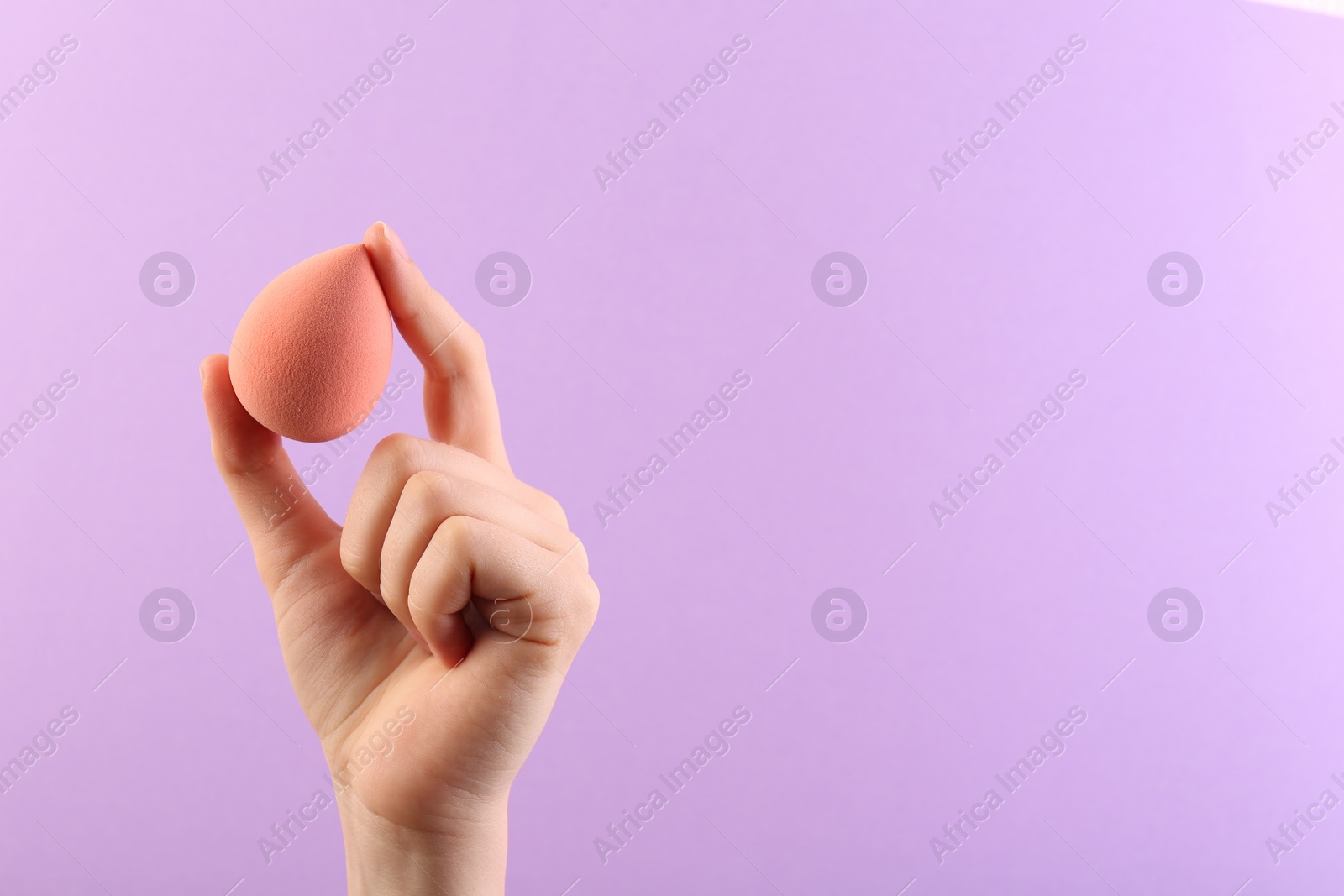 Photo of Woman with makeup sponge on violet background, closeup. Space for text