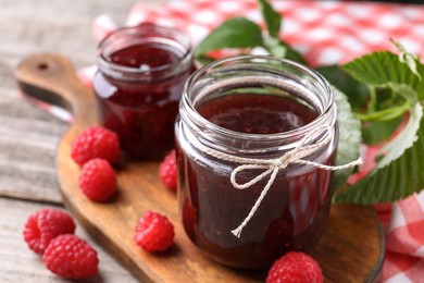 Photo of Delicious raspberry jam and fresh berries on table, closeup. Space for text