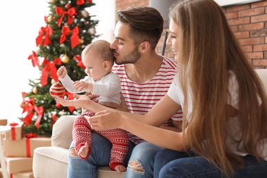 Photo of Happy couple with baby celebrating Christmas together at home