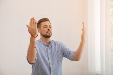 Photo of Muslim man with misbaha praying in light room