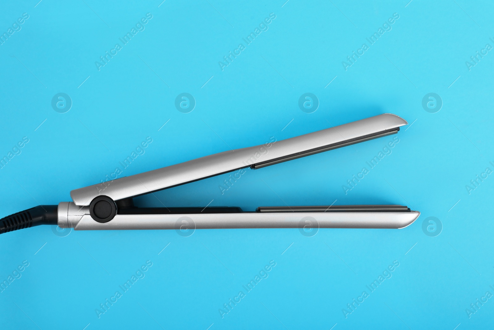 Photo of Modern hair iron for straightening on color background, top view