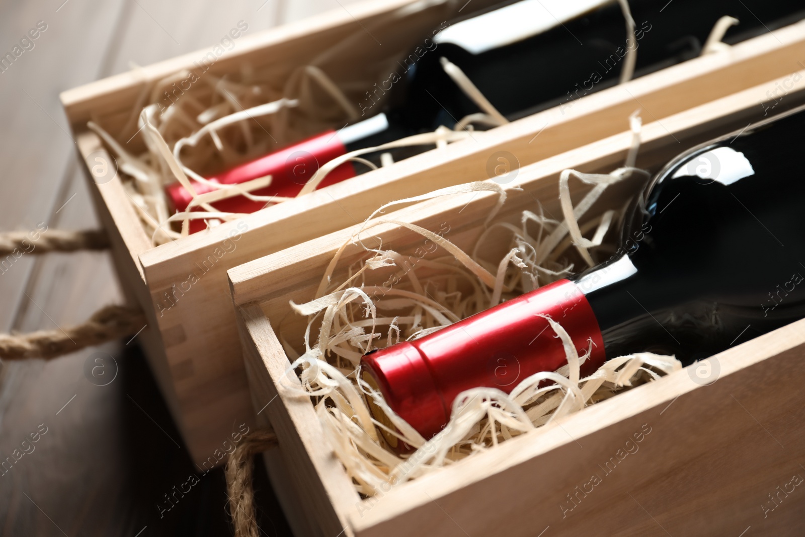 Photo of Bottles with delicious red wine in wooden boxes, closeup