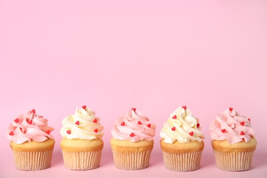 Photo of Row of tasty cupcakes on pink background, space for text. Valentine's Day celebration