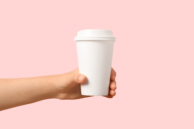 Photo of Woman holding takeaway paper coffee cup on pink background, closeup