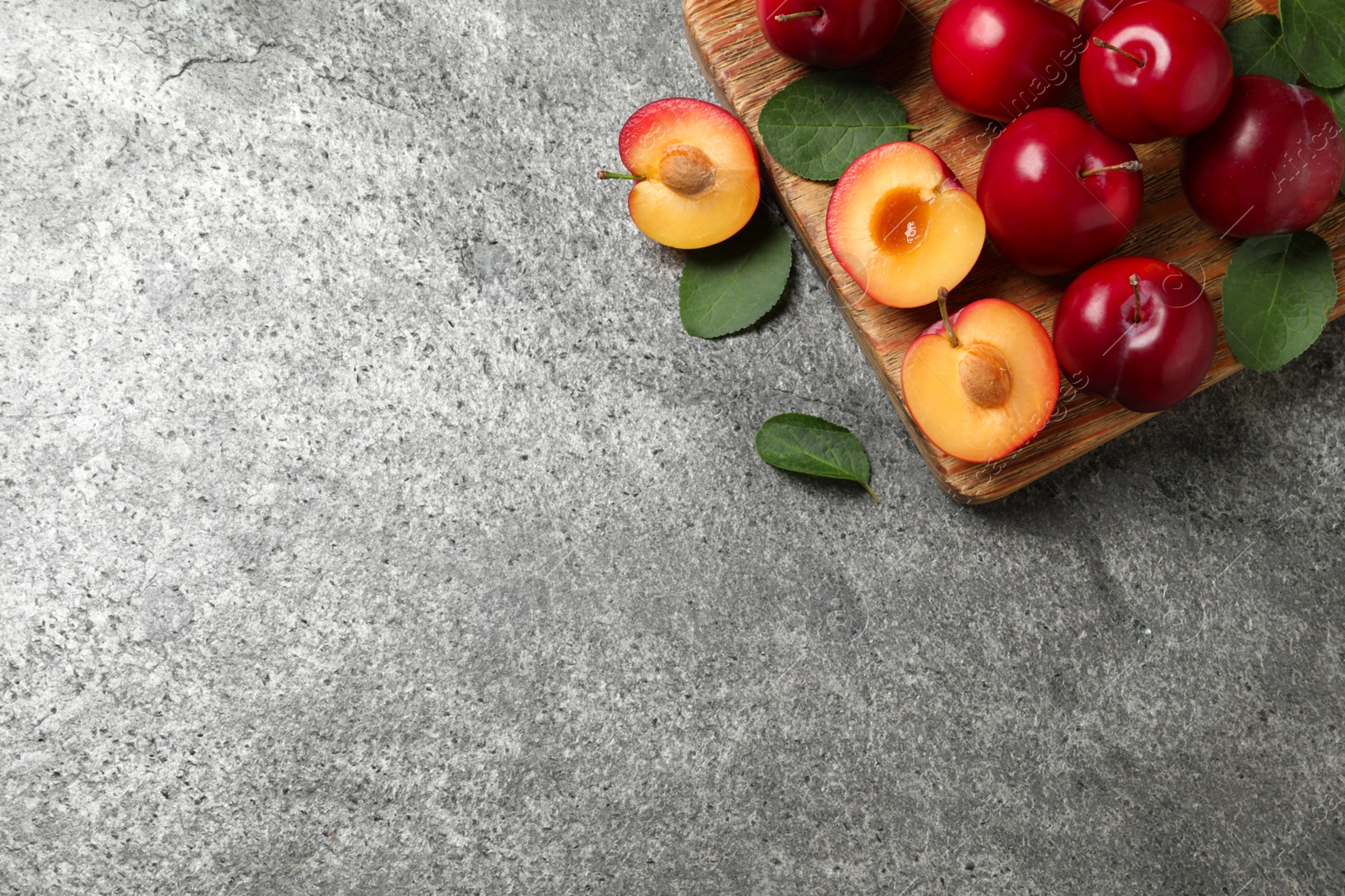 Photo of Fresh ripe cherry plums on grey table, flat lay. Space for text