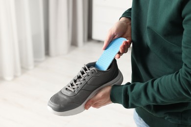 Photo of Man putting orthopedic insole into shoe indoors, closeup. Space for text