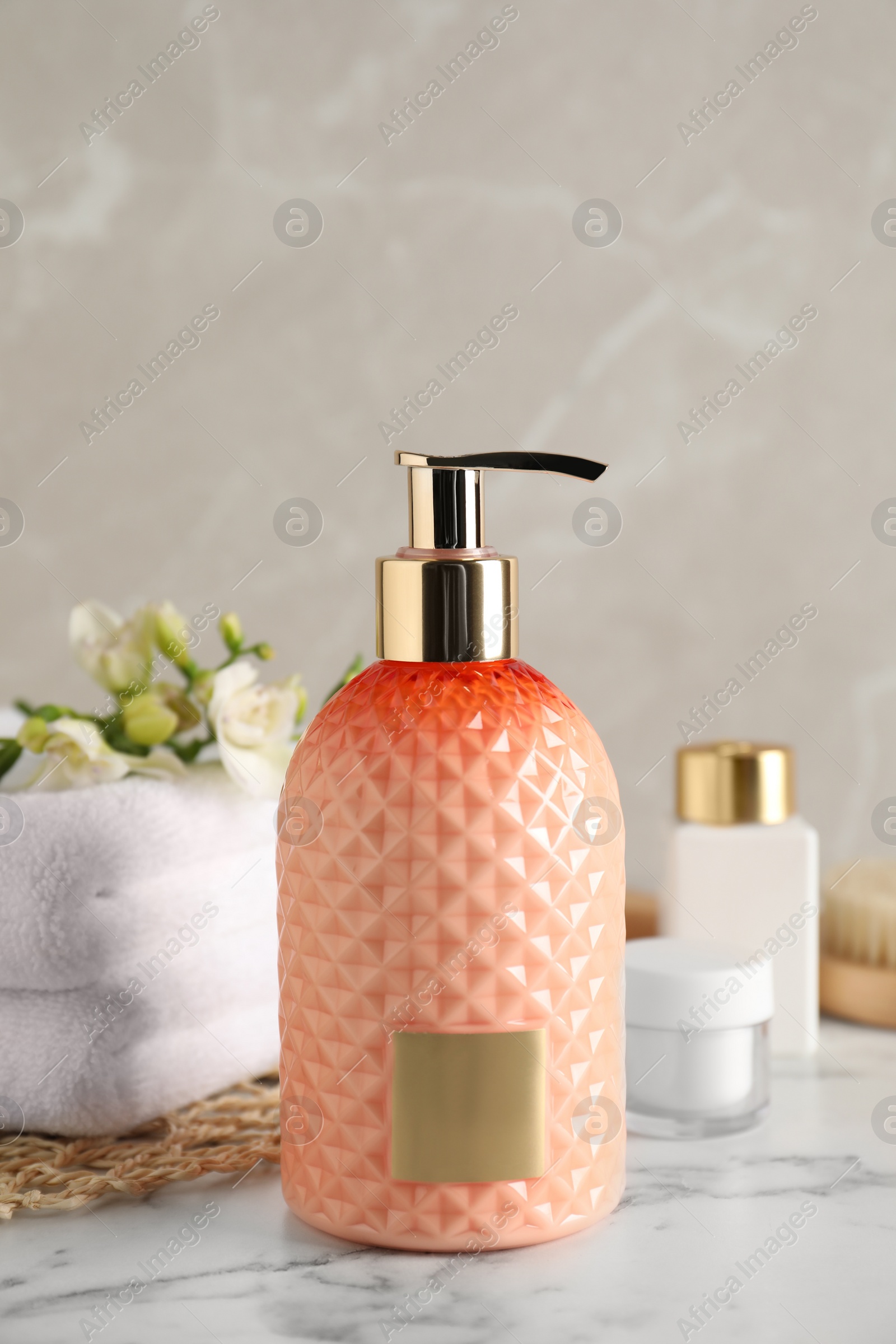 Photo of Stylish dispenser with liquid soap and other bathroom amenities on white marble table