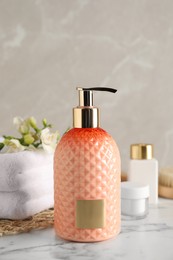 Photo of Stylish dispenser with liquid soap and other bathroom amenities on white marble table