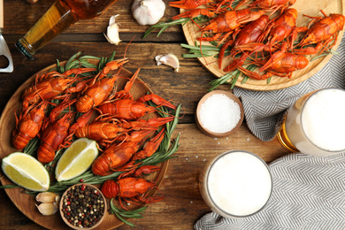 Flat lay composition with delicious red boiled crayfishes and beer on wooden table