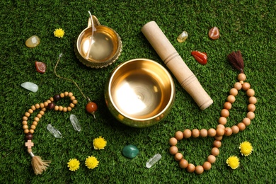 Flat lay composition with golden singing bowl on green grass. Sound healing