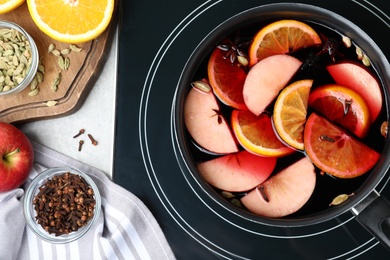 Photo of Delicious hot mulled wine on stove, flat lay