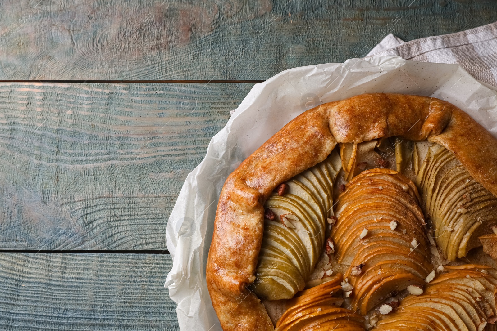 Photo of Delicious apple galette with pecans on wooden table, top view. Space for text