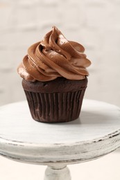 Photo of Delicious chocolate cupcake with cream on white stand, closeup