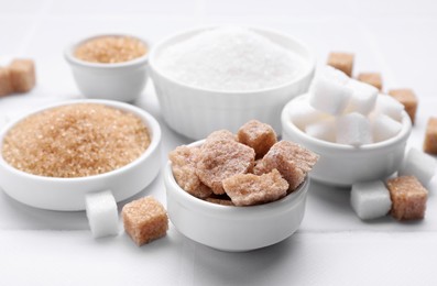 Different types of sugar on white table, closeup