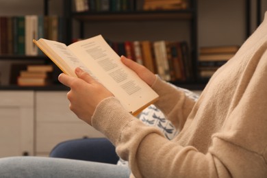 Photo of Young woman reading book in home library, closeup