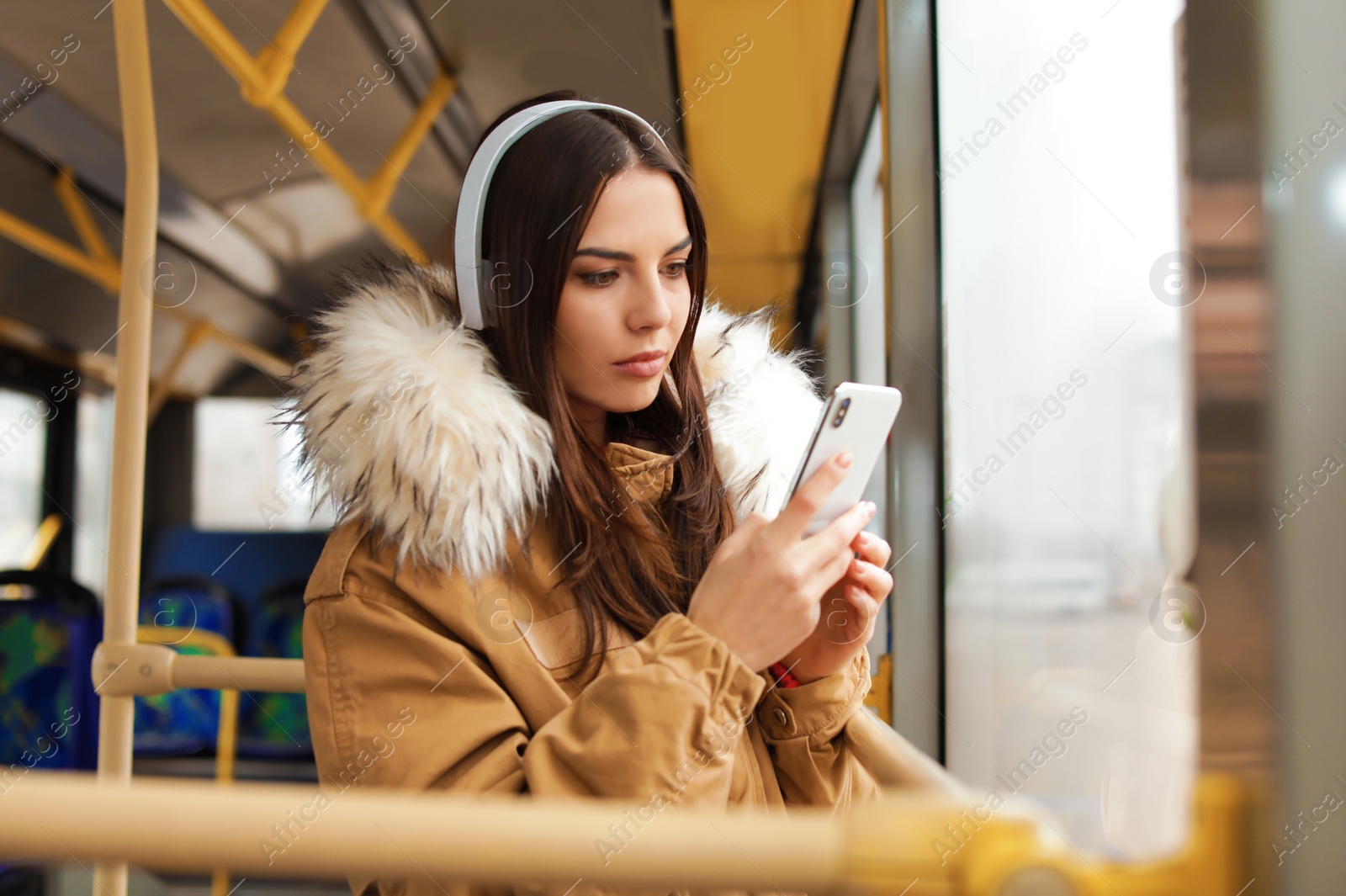 Photo of Young woman listening to music with headphones in public transport