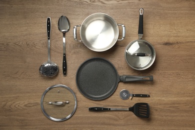 Photo of Set of cooking utensils on wooden table, flat lay