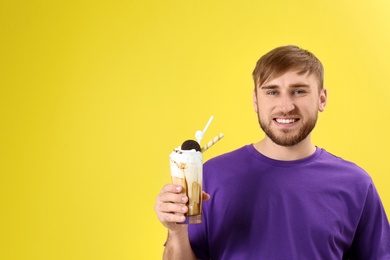 Photo of Young man with glass of delicious milk shake on color background