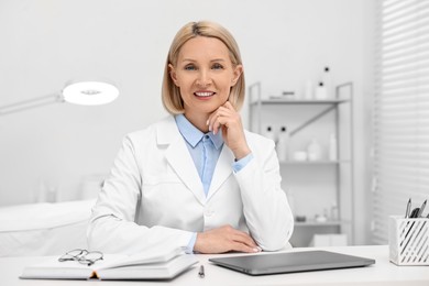 Photo of Portrait of happy dermatologist at white table in clinic