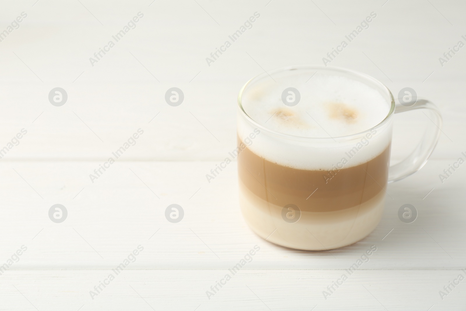 Photo of Aromatic coffee in glass cup on white wooden table, space for text