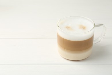 Photo of Aromatic coffee in glass cup on white wooden table, space for text