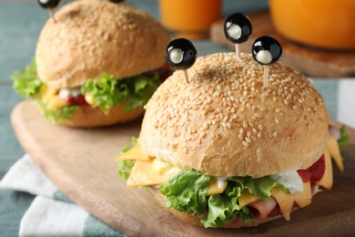 Cute monster burgers served on wooden board, closeup. Halloween party food