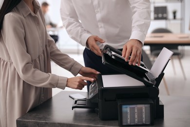 Photo of Employees using modern printer in office, closeup