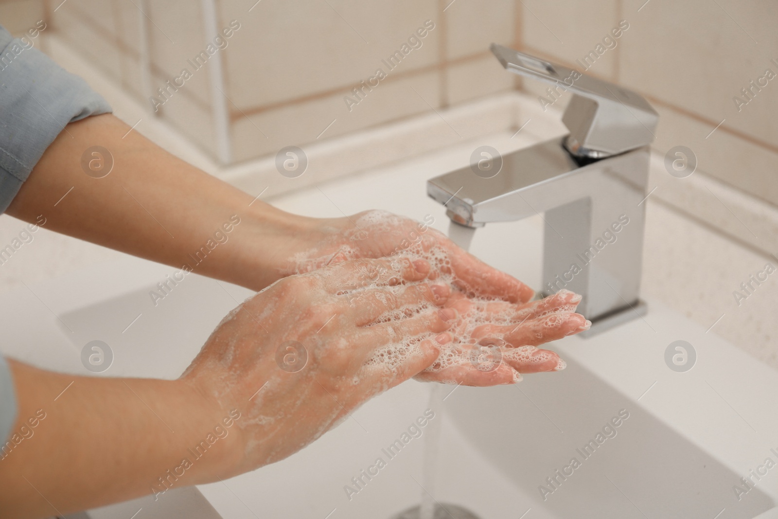 Photo of Woman washing hands with antiseptic soap in bathroom, closeup. Virus prevention