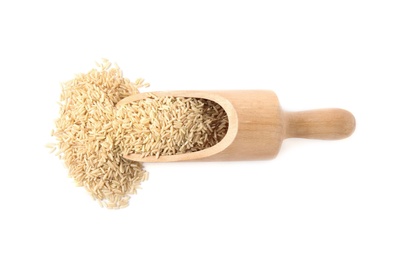 Photo of Scoop with uncooked brown rice on white background, top view