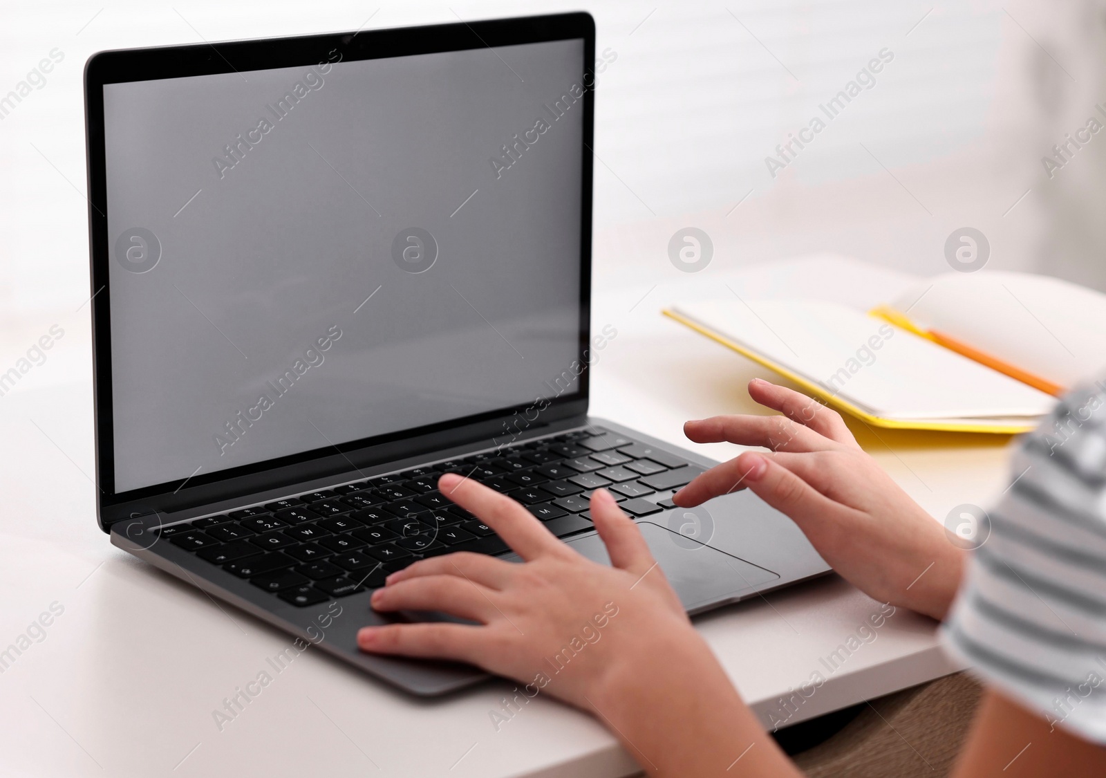 Photo of E-learning. Girl using laptop during online lesson at table indoors, closeup