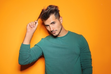 Photo of Young man with comb posing on color background. Trendy hairstyle