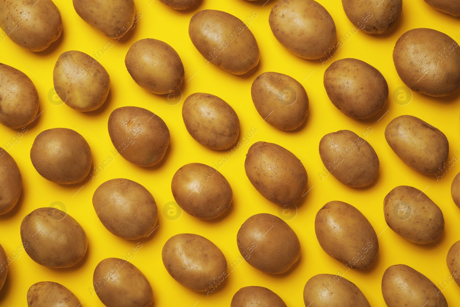 Photo of Raw fresh organic potatoes on yellow background, flat lay