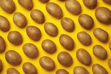 Raw fresh organic potatoes on yellow background, flat lay