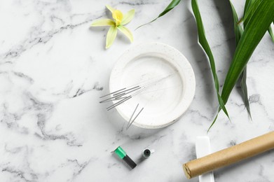 Photo of Flat lay composition with acupuncture needles on white marble table. Space for text