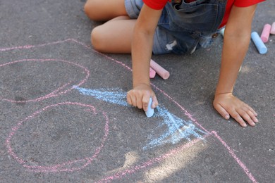 Little child drawing with colorful chalk on asphalt, closeup